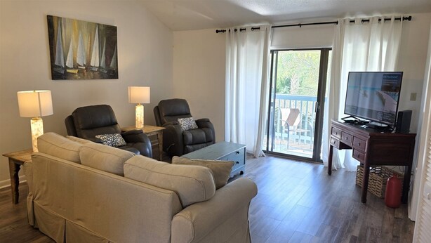 A living room with a sofa, two chairs, a coffee table, a TV, and a painting on the wall.