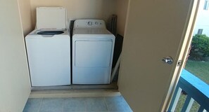 A laundry area with two washing machines and a door leading to an outdoor balcony.