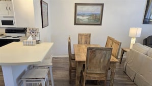 A kitchen with a wooden dining table and chairs, a white countertop, and a microwave.