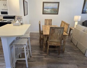 Una cocina con mesa y sillas de madera, una encimera blanca y un microondas.
