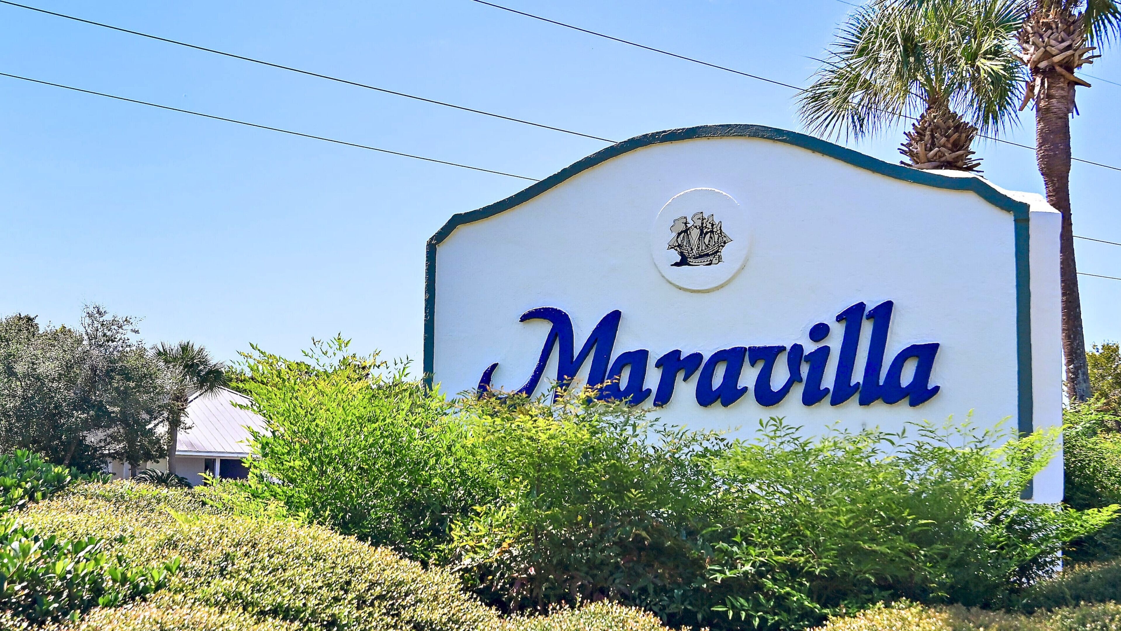 Une enseigne portant le nom « Maravilla » en lettres bleues, entourée de verdure.