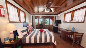 Ein Hotelzimmer mit Bett, Schreibtisch, Stuhl, Fernseher und einem fensterbepflanzten Fenster.