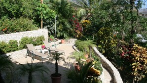 A patio area with stone walls, potted plants, and outdoor furniture. - Beautiful pool, 6-min walk from beach, ocean views - VILLAS CASA LOMA - Villa 4 (Playa Flamingo)