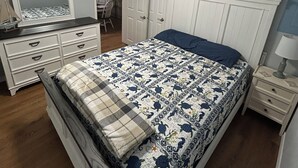 A bedroom with a bed, dresser, mirror, ceiling fan, and a wall sign. - 2-bedroom cabin over looking Kentucky Lake (Benton)