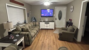 A living room with a sofa set, a television, a ceiling fan, and a clock on the wall. - 2-bedroom cabin over looking Kentucky Lake (Benton)