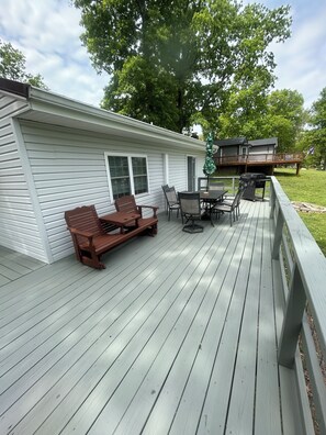 A covered deck with outdoor furniture, a grill, and a view of a house. - 2-bedroom cabin over looking Kentucky Lake (Benton)
