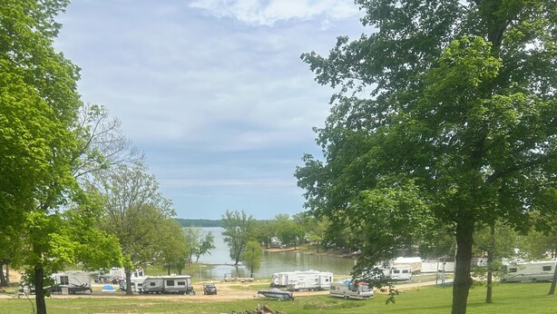 A barbecue grill on a deck overlooking a lake with RVs in the background. - 2-bedroom cabin over looking Kentucky Lake (Benton)
