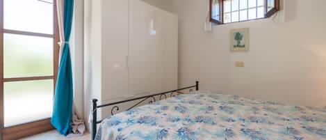 A bedroom with a bed, a wardrobe, a window, and a picture on the wall.