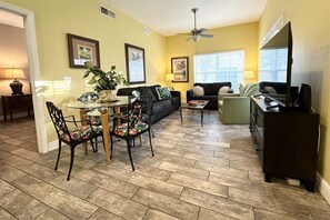 A living room with a dining table, chairs, sofas, a television, and a ceiling fan. - Venetian Bay 4 Bedroom in Quiet Location - VB014 (Kissimmee)