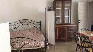 Ein Schlafzimmer mit einem Bett, einem Holzschrank, einem Schreibtisch und einem Stuhl.