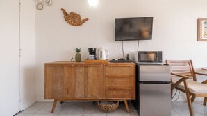 A compact kitchen with a wooden cabinet, a microwave, a coffee maker, and a small table with a chair. - ”Old Hawaii" Great Location at Waikiki (H7) (Honolulu)