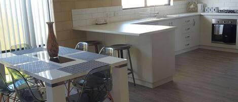 Een moderne keuken met een centraal eiland, witte kasten en een groot raam dat voor natuurlijk licht zorgt.