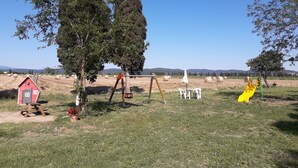 A rural landscape with a red barn, picnic table, swings, and hay bales. - Farmhouse Pescinone - Lavender, Etruscan Coast country and sea (Banditelle)