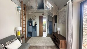 Una sala de estar acogedora con una escalera de madera, un estante azul, un tapete blanco y un banco de madera.