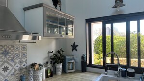 Una cocina moderna con horno integrado, cafetera y un amplio ventanal con vistas a zonas verdes.