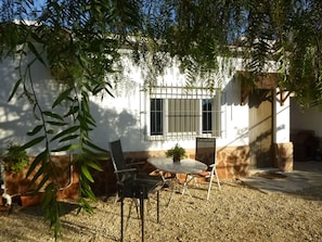 Eine Terrasse mit Tisch und Stühlen, umgeben von Kies und Kübelpflanzen.