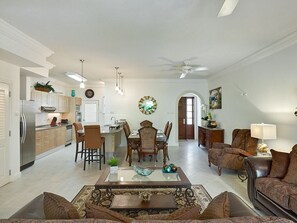 Ein geräumiges Wohnzimmer mit Essbereich, Küche und Deckenventilator.