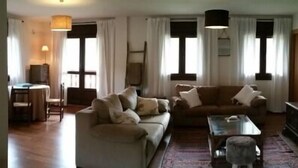 Un salon avec un canapé, une table basse, un téléviseur et une cheminée.