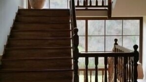 Un escalier en bois, doté d’une balustrade, mène à un palier situé au deuxième étage.
