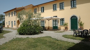 A building with a yellow facade, green doors, and a patio area with outdoor seating.