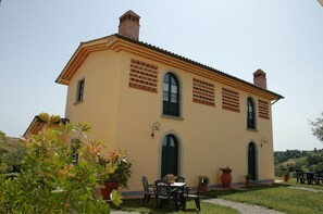 Un bâtiment à deux étages, doté d  ’une façade jaune, de fenêtres en arc de cercle et d’une cheminée en briques.