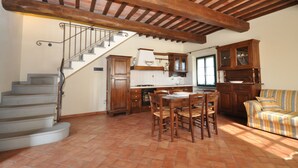 A kitchen with a dining table, chairs, a staircase, and wooden cabinets.