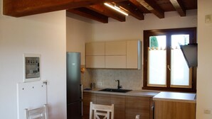 A compact kitchen with wooden cabinets, a built-in sink, and a dining area with a wooden table and chairs.
