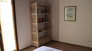 A room with a bed, a wooden bookshelf, and a framed picture on the wall.