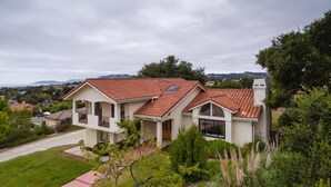 A two-story house with a red-tiled roof, a covered porch, and a well-maintained lawn.