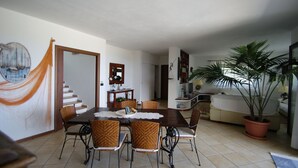 A dining area with a wooden table, wicker chairs, a lace tablecloth, and a potted plant. - beautiful detached villa with private pool wi-fi (Briatico)