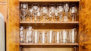 Una cocina con estantes de madera que exhiben diferentes vasos y una cafetera.