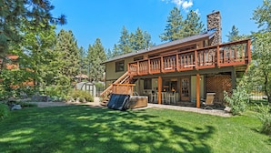 Una casa de dos pisos con un porche de madera y una chimenea de piedra.