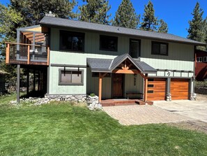 A modern two-story house with a balcony, a covered porch, and a garage.