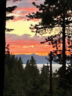 Sonnenuntergang mit Bergen im Hintergrund und Bäumen im Vordergrund.