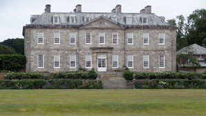 Un grand bâtiment en pierre, doté d’une façade symétrique, de nombreuses fenêtres et d’une entrée centrale.