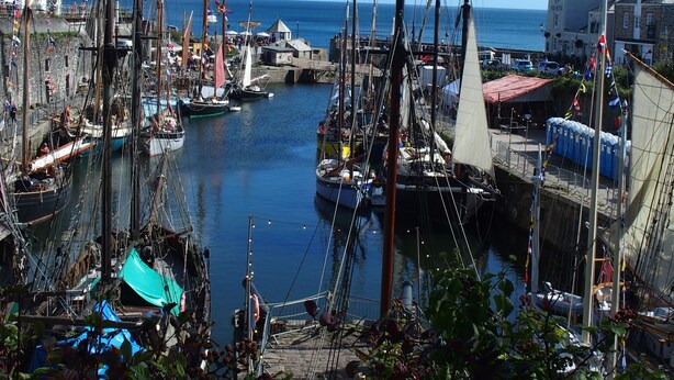 Un port où de nombreux bateaux sont amarrés, un ciel dégagé et des bâtiments qui bordent la promenade.