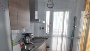 A kitchen with wooden cabinets, a stainless steel sink, a coffee maker, and a window with curtains. - Townhouse in front of Botanical Garden, Salinas and Natural Park (Lo Pagan)