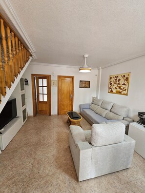 A living room with a sofa, a television, a coffee maker, and a ceiling fan. - Townhouse in front of Botanical Garden, Salinas and Natural Park (Lo Pagan)