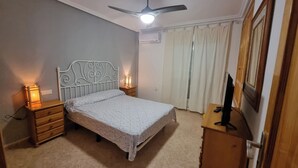 A bedroom with a bed, nightstands, a ceiling fan, an air conditioner, and a television. - Townhouse in front of Botanical Garden, Salinas and Natural Park (Lo Pagan)