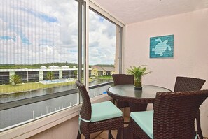 Ein Balkon mit Korbmöbeln, Blick auf ein Gewässer und ein Gebäude im Hintergrund.