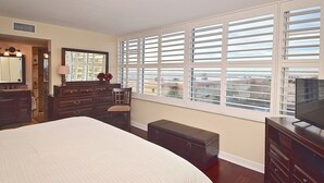 Ein Schlafzimmer mit einem großen Bett, einem Schminktisch, einem Spiegel, einer Bank und einem Fernseher.