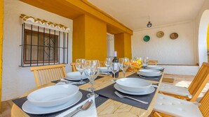 A dining area with a long table set for a meal, featuring white plates, glasses, and cutlery.
