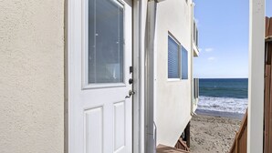 Una puerta blanca con ventana que da a vistas de la playa.