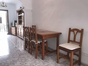 A dining area with a wooden table and chairs, a cabinet with glass doors, and a marble floor.