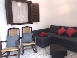 A living room with two wooden chairs, a dark sofa, and a red blanket.