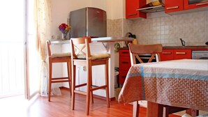 Uma cozinha compacta com cadeiras de madeira, uma mesa de jantar e armários vermelhos.