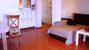 Quarto com cama, cadeira, mesinha, penteadeira e porta.
