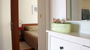 Um quarto com cama, mesa de cabeceira, cômoda e espelho.