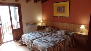 Een slaapkamer met twee bedden, een houten hoofdbord, nachtkastjes met lampen, een radiator en een raam met uitzicht.
