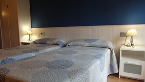 Een slaapkamer met twee bedden, een kledingkast, nachtkastjes met lampen en een nachttafeltje.